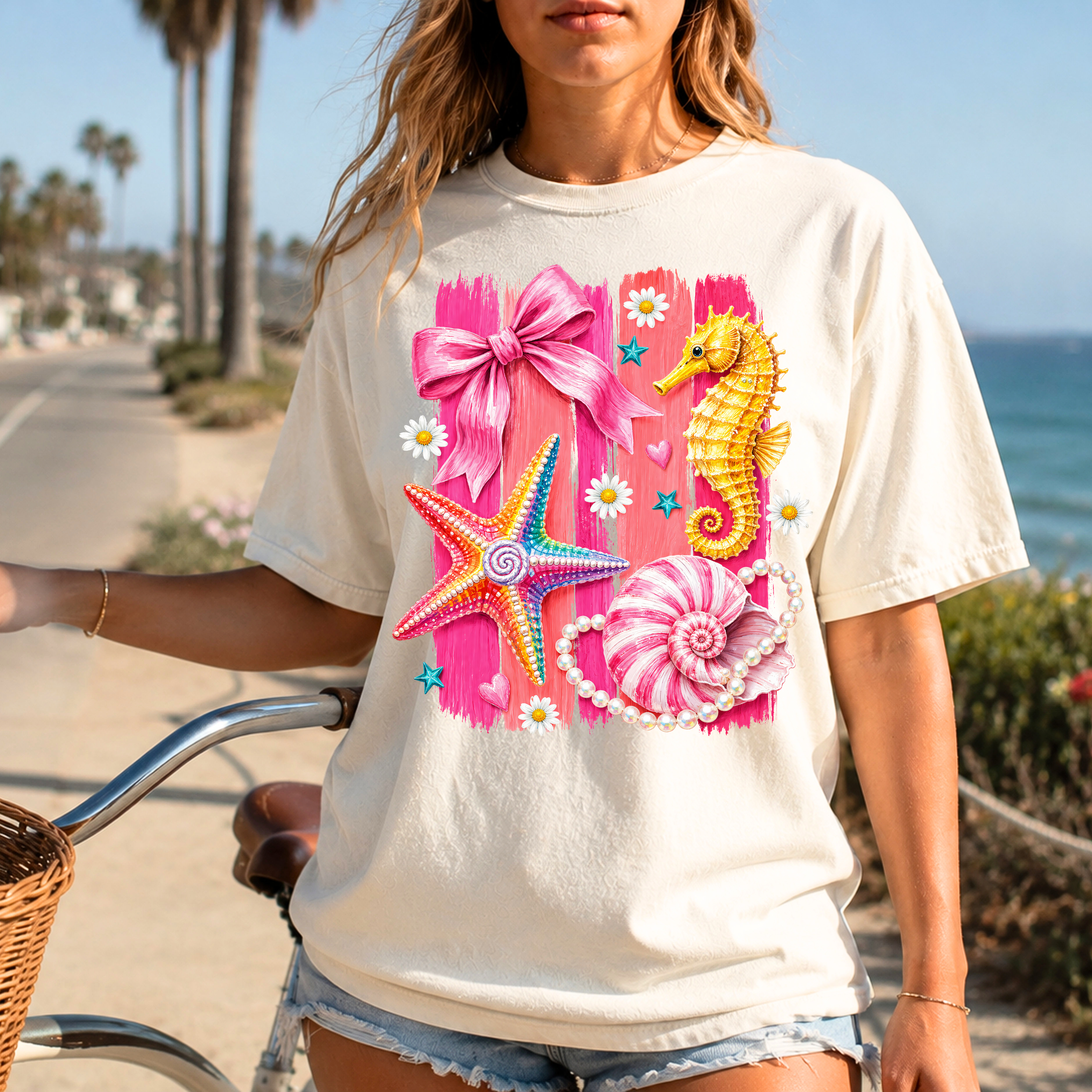 Ivory coastal graphic tee with pink seahorse, starfish, seashell, and bow artwork perfect for beach vacations and summer outfits.