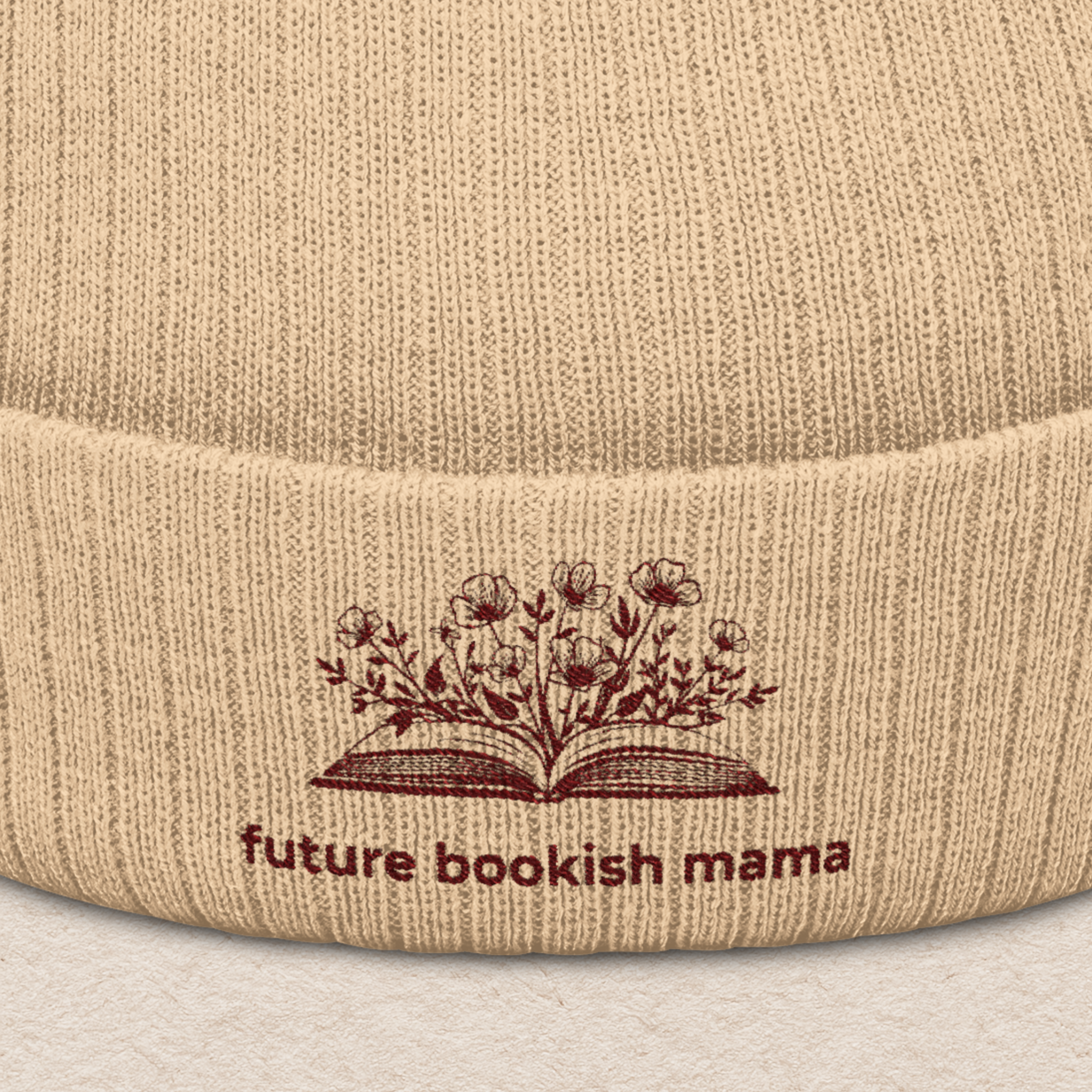 Close-up embroidery detail of “Future Bookish Mama” text and book design on beige knit beanie