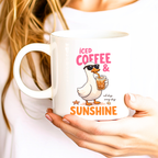 Woman holding iced coffee and sunshine mug featuring cute duck coffee lover design
