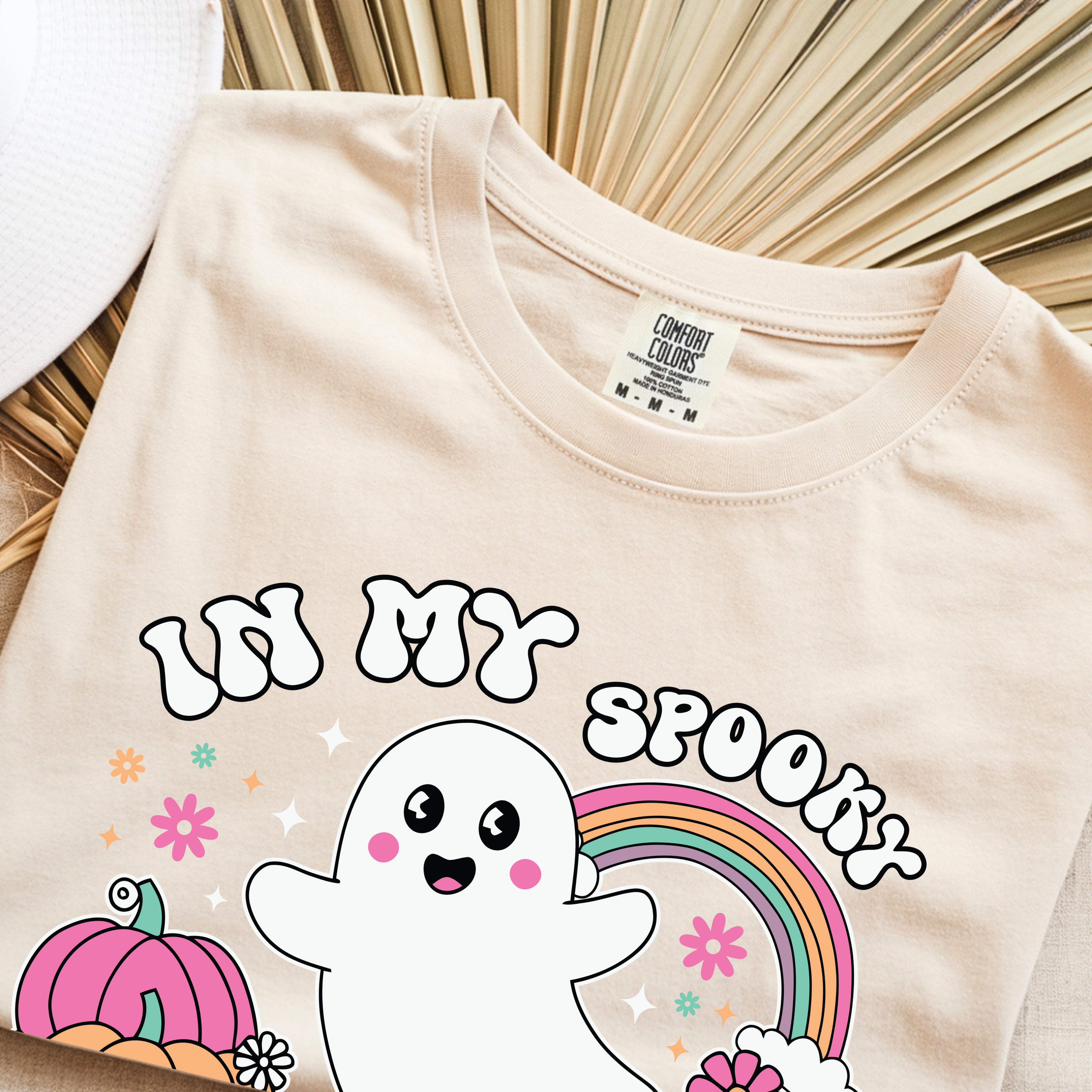 Folded Halloween pregnancy shirt featuring ghost pumpkin and rainbow artwork