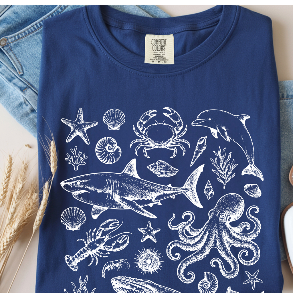 Navy Ocean Life graphic t-shirt displaying detailed marine wildlife artwork including whale, dolphin, sea turtle and coral illustrations.