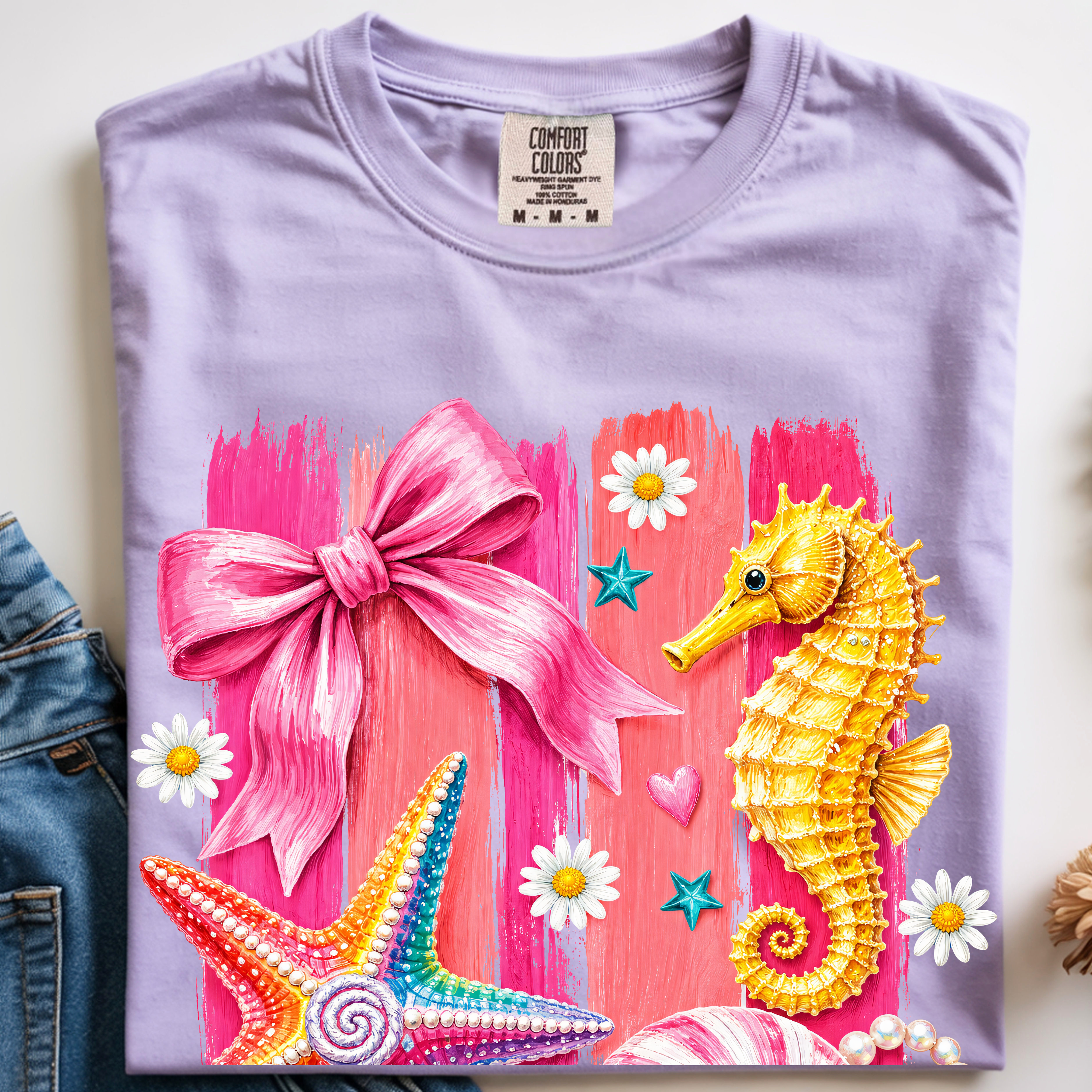 Orchid purple coastal graphic t-shirt featuring seashells, starfish, seahorse, pearls, and feminine beach-inspired artwork.