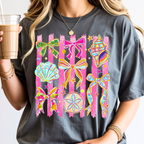 Woman wearing pepper color coastal graphic tee featuring colorful seashells ribbons and beach inspired artwork